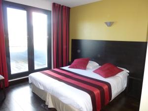 Un dormitorio con una cama grande con almohadas rojas. en Logis Hôtel Terre de Loire, en Belleville-sur-Loire