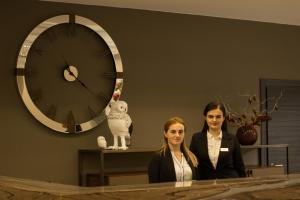 two women are standing in front of a clock at Hotel Irys by Derenivska Kupil in Nyzhne Solotvyno