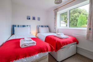 two beds in a room with red and white sheets at Beaver Cottage in Aldeburgh