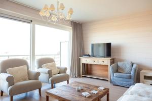 uma sala de estar com uma televisão, cadeiras e uma mesa em Apartment Zonnehaven em Nieuwpoort