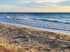 a sandy beach with waves in the ocean at 5 person holiday home in Aakirkeby in Åkirkeby