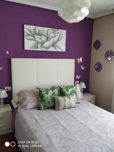 - une chambre avec des murs violets et un lit avec des oreillers dans l'établissement Apartamento Dreams, à Vigo