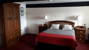 um quarto com uma cama com um cobertor vermelho e um armário de madeira em Waterside Guesthouse em Graiguenamanagh