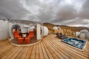 a house on a deck with a table and chairs at Petra Bubble Luxotel in Wadi Musa