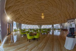 a restaurant with a large wooden ceiling and green chairs at Petra Bubble Luxotel in Wadi Musa