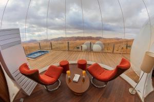 Zimmer mit einem Tisch und Stühlen auf einem Balkon in der Unterkunft Petra Bubble Luxotel in Wadi Musa