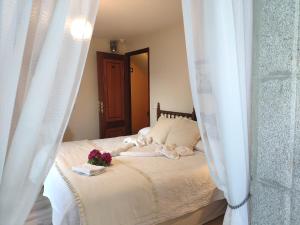 1 dormitorio con 1 cama con cortinas blancas y flores en Pensión Pura, en Cuntis