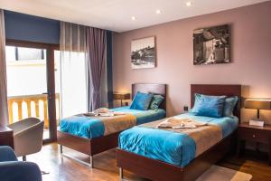 2 Betten in einem Hotelzimmer mit blauer Bettwäsche in der Unterkunft Havana Resort in Antananarivo