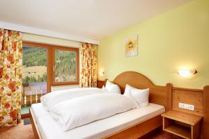 a bedroom with a large white bed with a window at Gästehaus Strasser in Riezlern