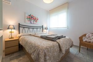 - une chambre avec un lit, une fenêtre et une chaise dans l'établissement Apartamentos Vado - Sendero del Veleta, à Cenes de la Vega