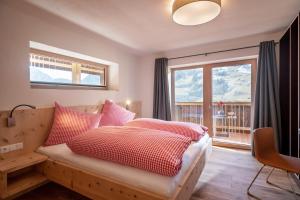 a bedroom with a bed with red and white pillows at Apartments Zauberberg in Hainzenberg