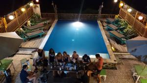 a group of people sitting at a table in front of a pool at Green Paddy Hostel & Villa in Ubud