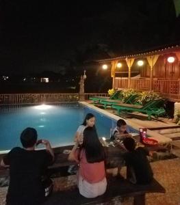 un grupo de personas sentadas alrededor de una mesa junto a una piscina en Green Paddy Hostel & Villa, en Ubud