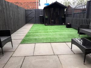 a backyard with a lawn with chairs and a fence at Oldwood Place Townhouse in Livingston