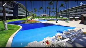 a swimming pool with lounge chairs and a resort at Ancorar Flat Resort Porto de Galinhas in Porto De Galinhas