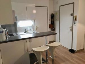 - une cuisine avec un évier et deux tabourets dans l'établissement Chaleureux appartement en centre ville de Poitiers, à Poitiers