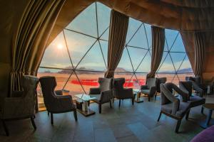 una stanza con sedie e tavoli e una grande finestra di Wadi Rum UFO Luxotel a Wadi Rum