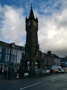 a clock tower in the middle of a city at Tri deg un, cottage for 2 adults and 2 children in Machynlleth