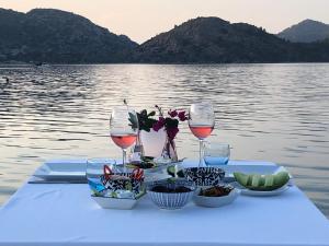 a table with glasses of wine and bowls of food at Beyaz İskele Hotel & Restaurant in Selimiye