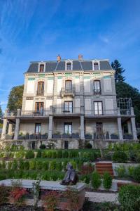 un grand bâtiment avec une statue en face dans l'établissement Villa Saint Enogat, à Aix-les-Bains