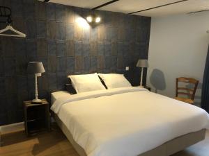 a bedroom with a large white bed with a wooden wall at Cuerne bed&breakfast in Kuurne