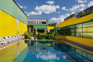 a swimming pool next to a yellow building with chairs at Vienna Sporthotel in Vienna