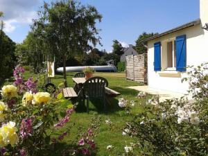 un jardín con mesa, sillas y flores en Bungalow de Kermoal en Trébrivan