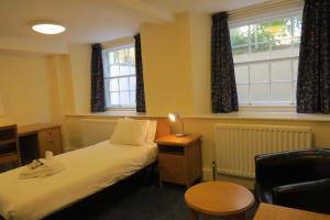 a room with a bed, chair and a lamp at Wadham College in Oxford