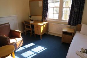 a room with a bed, chair, desk and a lamp at Wadham College in Oxford