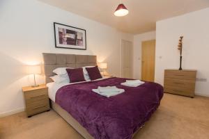 a bedroom with a purple bed with two night stands at Catchpole Stays Abbey Field Apartment- A lovely 2 bed apartment with field views near Colchester town centre in Colchester