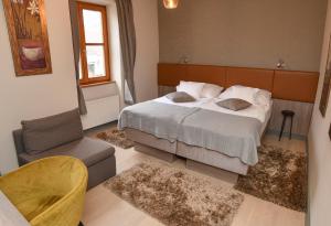 ein Schlafzimmer mit einem Bett, einem Sofa und einem Stuhl in der Unterkunft Portré Panzió in Kőszeg