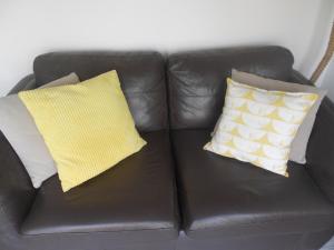 Un sofá de cuero marrón con dos almohadas. en Villa Farm Cottage, en Thornton Curtis