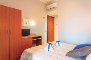 a bedroom with a bed and a desk with a television at Hotel Tritone Rimini in Rimini