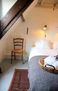 a bedroom with a bed with a chair and a chair at Huisje Vogelenzang Zeeland in Sint Annaland