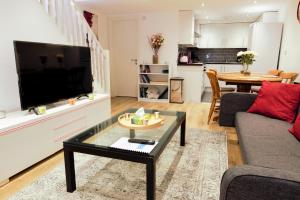 a living room with a large television and a table at STYLISH 2 BEDROOM APARTMENT IN THE HEART OF GREENWICH in London