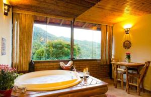 bañera grande en una habitación con ventana grande en Pousada Moriá, en Visconde De Maua