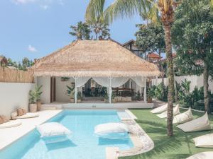 an outdoor swimming pool with a thatched umbrella and palm trees at Arya Wellness - female only in Ubud