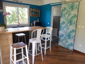 una cocina con taburetes blancos y una barra con ventana en Suite exotique, en Étang-Salé