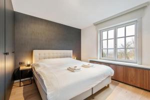 a bedroom with a white bed and a window at Big modern and bright villa near coast in Koksijde