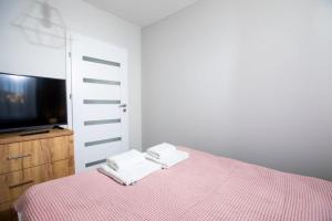 een slaapkamer met een bed met roze lakens en een televisie bij Resort Apartamenty Klifowa Rewal 29 in Rewal