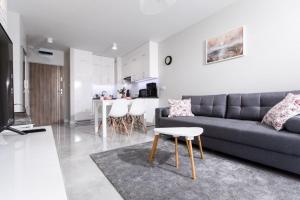 a living room with a gray couch and a kitchen at Resort Apartamenty Klifowa Rewal 29 in Rewal