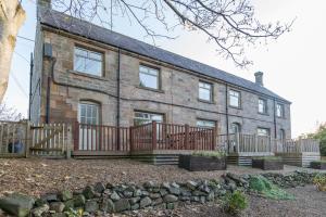 a brick house with a wooden fence in front of it at Host & Stay - Poppy Cottage in Bamburgh