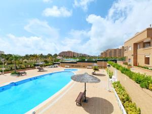 una piscina al aire libre con sombrilla, sillas y mesas en Apartment Jardines del Mar - Azahar by Interhome, en El Borseral