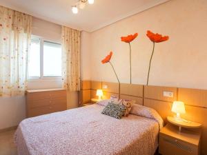 1 dormitorio con 1 cama con 3 flores en la pared en Apartment Jardines del Mar - Azahar by Interhome, en El Borseral