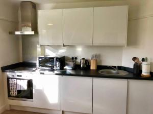 a kitchen with white cabinets and a sink at Ashbrook Harwell (a) in Harwell