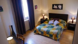 a bedroom with a bed with a colorful comforter at HOTEL Restaurant LE CALDERO in Montpon-Ménestérol