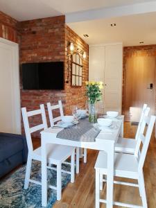 een witte eetkamer met een witte tafel en stoelen bij Apartamenty NAUTICA Gdańsk in Gdańsk