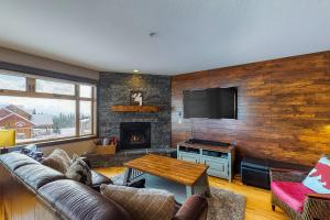 Una sala de estar con un sofá y una chimenea. en Raven 104, en Big White