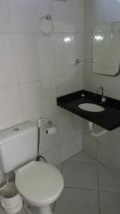 a white bathroom with a toilet and a sink at Hotel Arco-Íris in Itapipoca