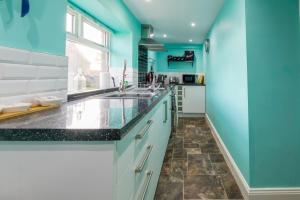 a kitchen with blue walls and a sink at Host & Stay - Poppy Cottage in Bamburgh